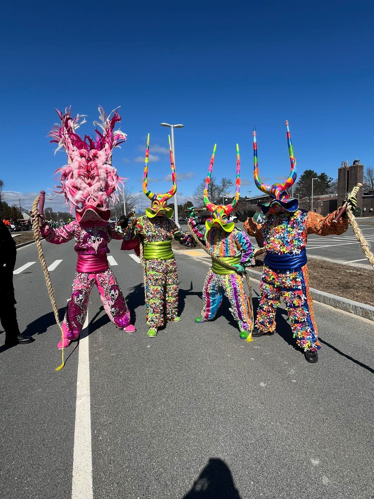 A line of pink and magenta Diablos Cojuelos dancing in formation down the street