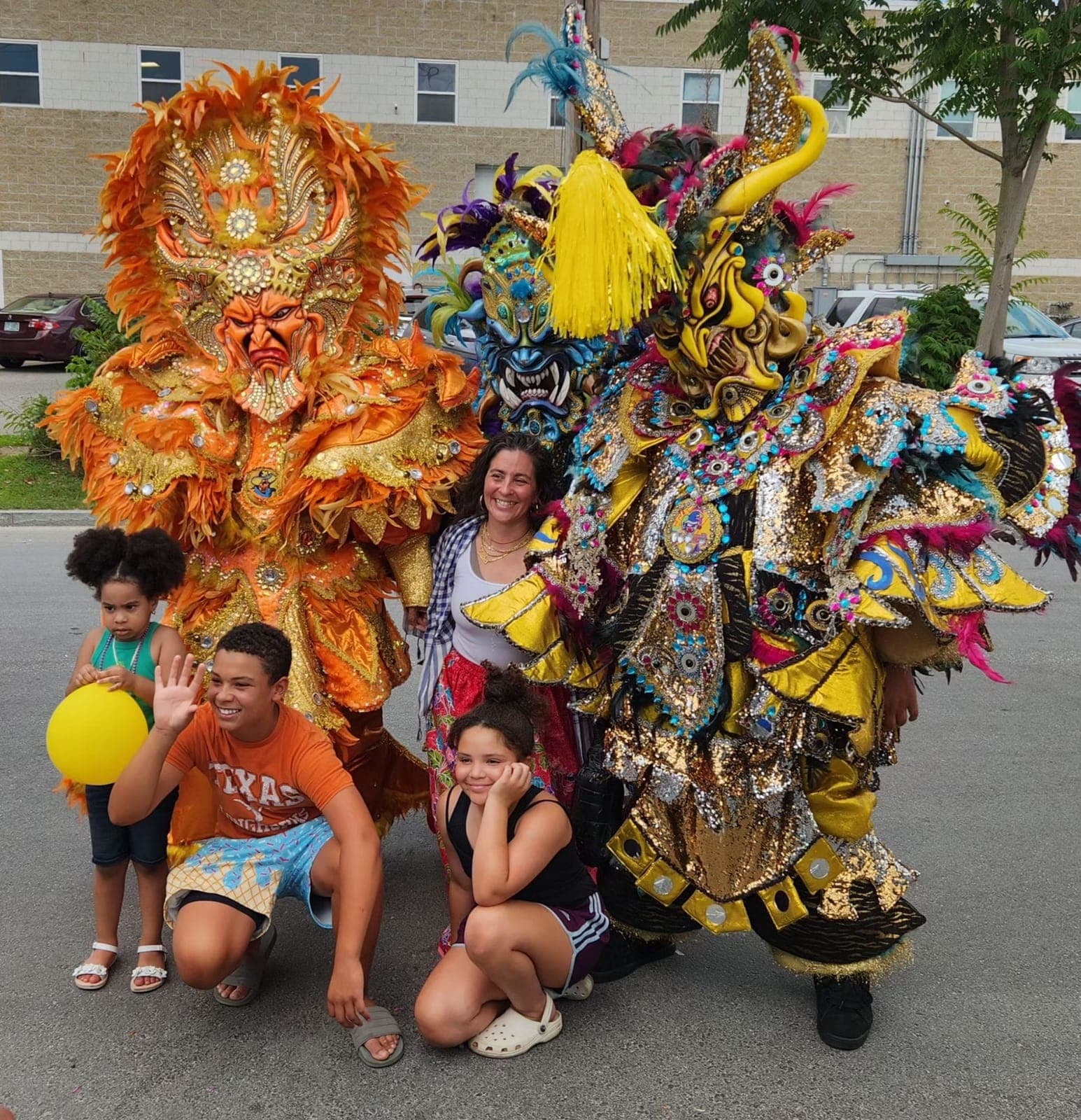 A family poses with two performers in ornate orange and gold Diablo Cojuelo costumes